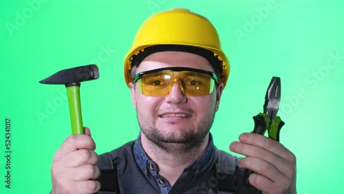 Professional male builder on green screen. he holds tools in his hands and smiles at the camera  photo