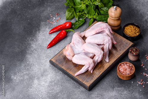 Raw chicken wings with ingredients for cooking on a wooden cutting board