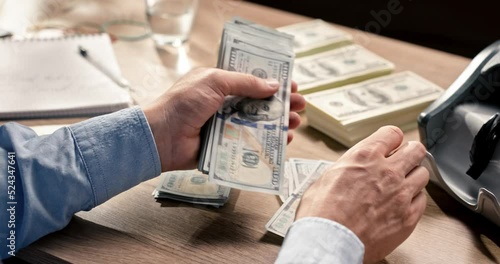 Male hands counting dollar banknotes sitting in room at table. Banking and finance. Business lifestyle. Rich man hands holding cash money in bank cabinet. Financial job concept. Close up shot