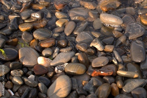 A pure transparent sea wave rolls over the rocky pebble shore, the concept of rest and travel, tranquility, relaxation and reflection on a warm summer day, close-up.