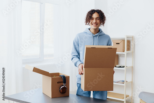 A young man cardboard boxes in the room unpacking interior © SHOTPRIME STUDIO