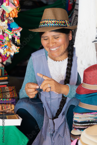 Mujer latina sonriendo y tejiendo en una típica tienda de recuerdos