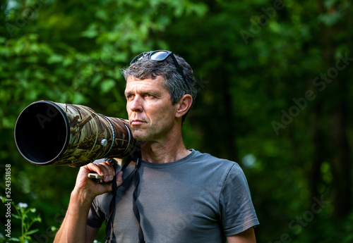 Man with zoom lens on shoulder in nature photo