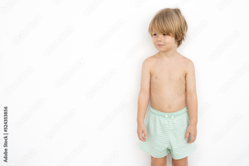 Child boy smiling happy standing against white wall in a summer day. Concept of activity and happy childhood. Child boy smiling happy standing against white wall in a summer day. Concept of activity and happy childhood.