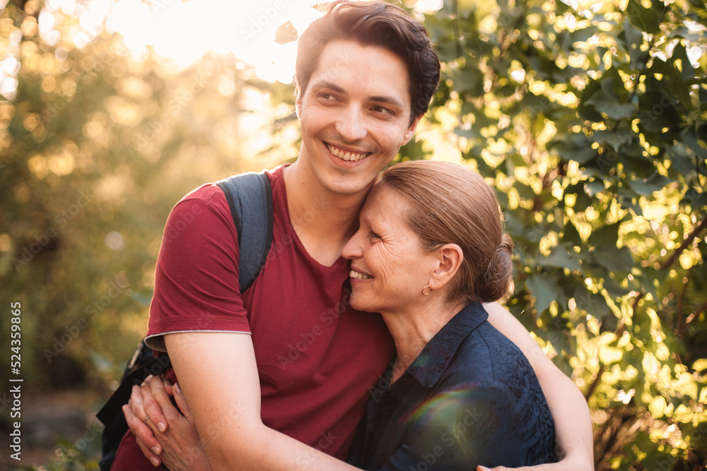 Happy son embracing smiling mother outdoors in summer Happy son embracing smiling mother outdoors in summer
