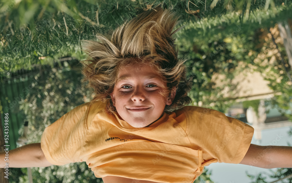 Kid Hanging Upside Down While Playing Outdoors At Backyard Stock Photo