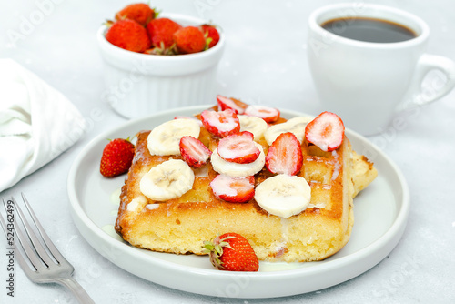 Square belgian waffles with strawberries berries,bananas,condensed milk,honey on plate, cup of coffee espresso. Tasty breakfast, sweet dessert food.selective focus, close up top view flat lay