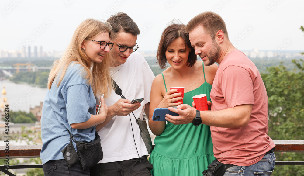 Fototapeta premium a company of friends uses a smartphone takes a selfie on the background of the city panorama.