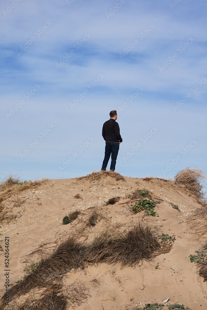 Vertical shot of young man on top of dune in El Saler beach in Valencia Vertical shot of young man on top of dune in El Saler beach in Valencia