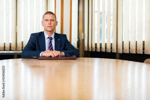 Stylish confident young man with briefcase waiting for job interview at office