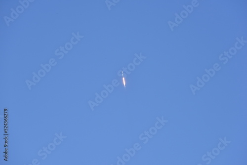 Distant Rocket Launch clear Blue Day with exhaust trail and sunny sky
