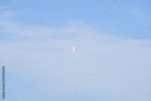 Distant Rocket Launch clear Blue Day with exhaust trail and sunny sky