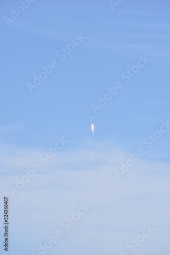 Distant Rocket Launch clear Blue Day with exhaust trail and sunny sky