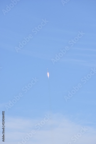 Distant Rocket Launch clear Blue Day with exhaust trail and sunny sky