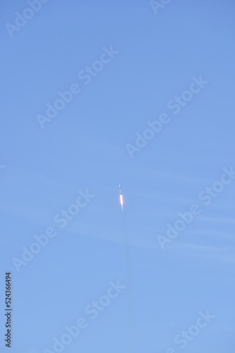 Distant Rocket Launch clear Blue Day with exhaust trail and sunny sky