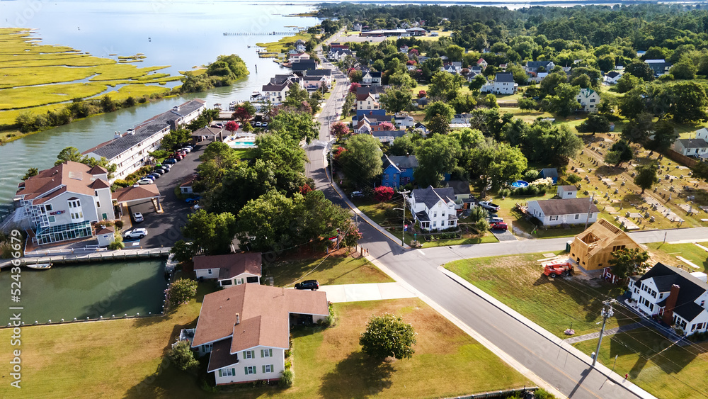 Chincoteague Island, residential areas and marinas, houses and motels with car parks. bridge and road along the bay. Drone view.