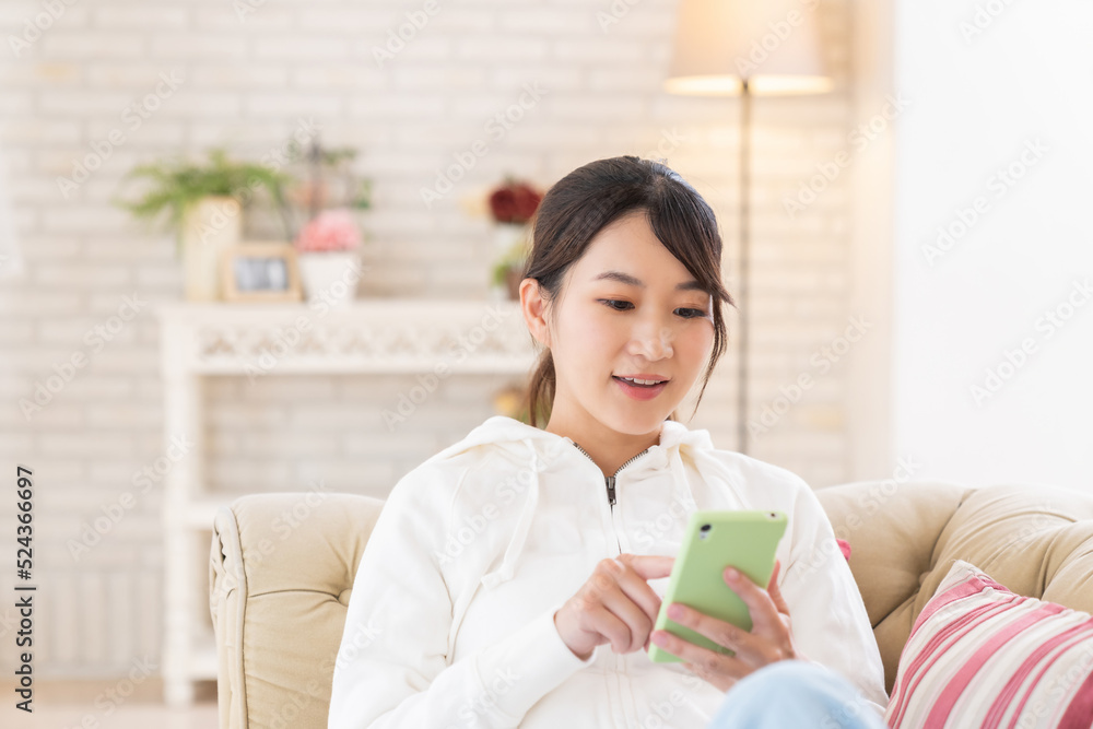部屋でスマホを見る女性 部屋でスマホを見る女性