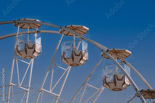 Beautiful top part of ferris wheel with cabins on blue sky background