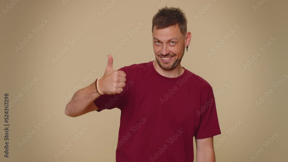 Look at advertisement. Bearded handsome young man pointing down, saying to subscribe, gesturing ok and like, showing place for commercial, promotional information below. Adult guy on beige background Look at advertisement. Bearded handsome young man pointing down, saying to subscribe, gesturing ok and like, showing place for commercial, promotional information below. Adult guy on beige background