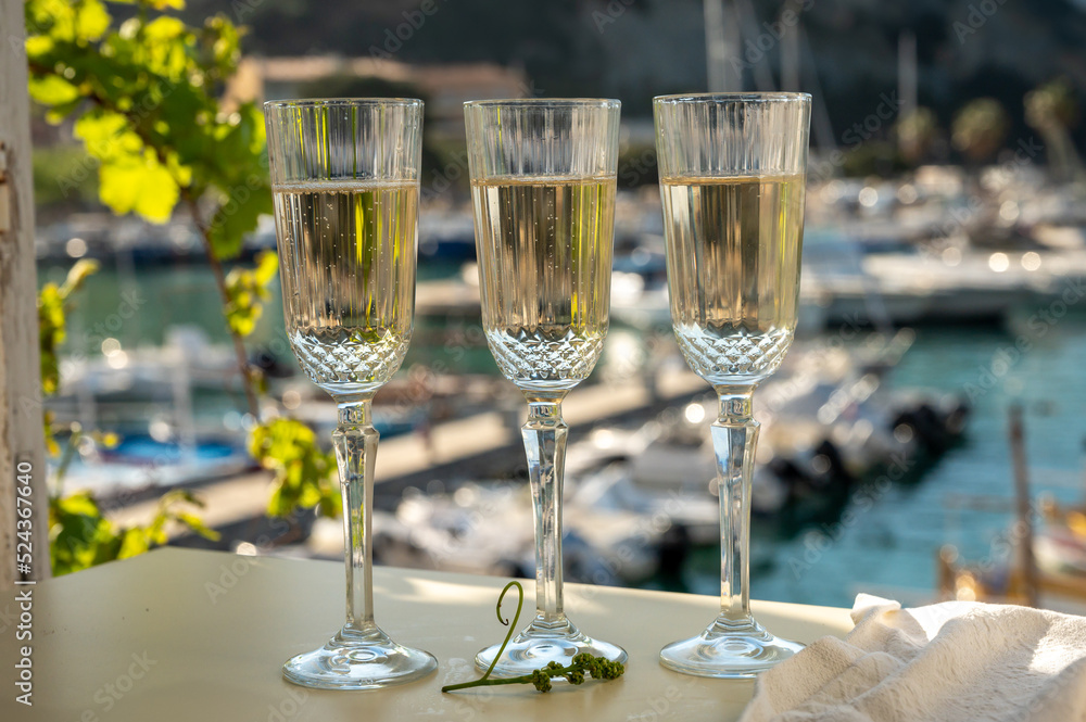 Three glasses of French champagne sparkling wine and view on colorful fisherman's boats in old harbour in Cassis, Provence, France Three glasses of French champagne sparkling wine and view on colorful fisherman's boats in old harbour in Cassis, Provence, France