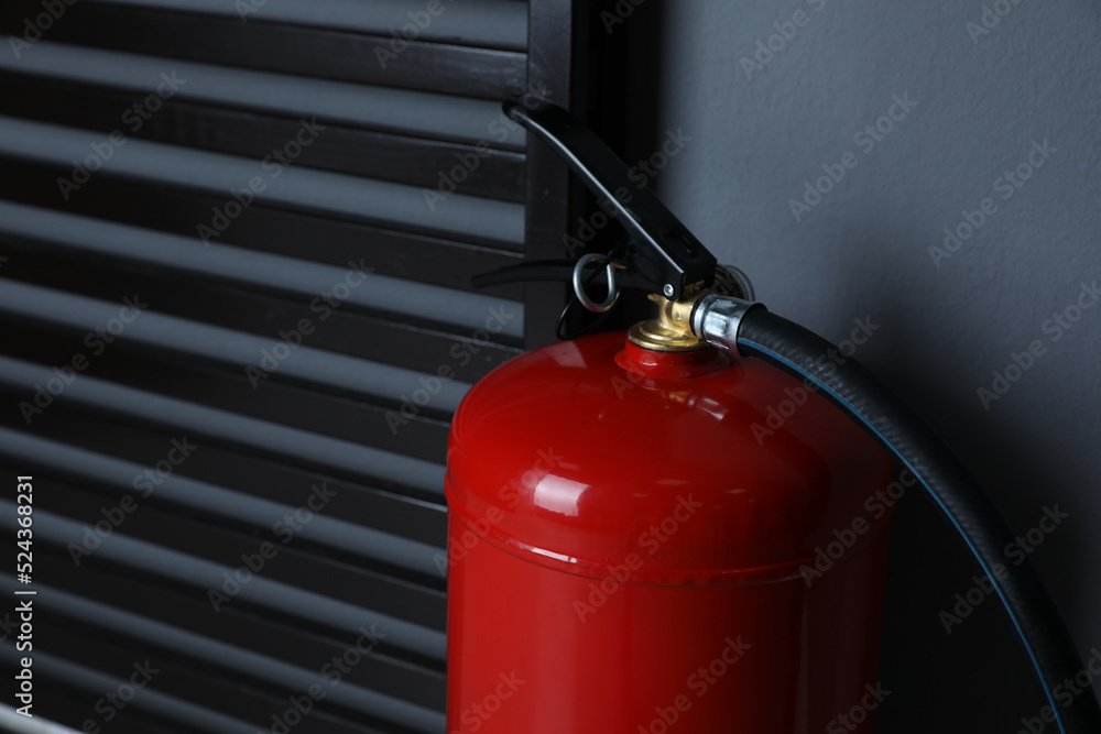 Fire extinguisher near grey wall indoors, closeup. Space for text Fire extinguisher near grey wall indoors, closeup. Space for text