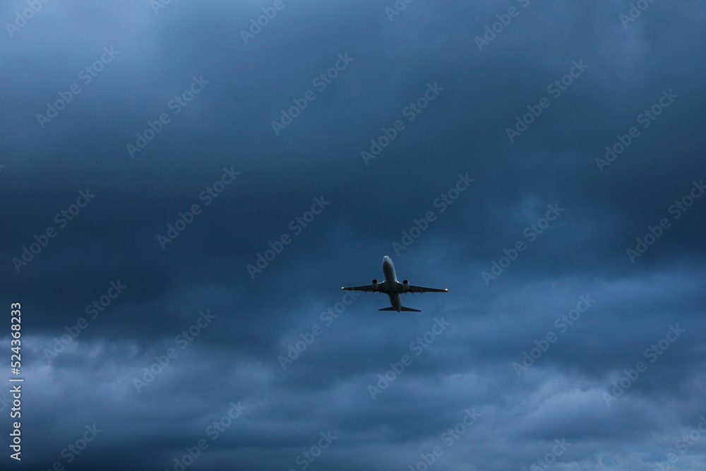 Modern white airplane flying in sky with clouds, low angle view Modern white airplane flying in sky with clouds, low angle view