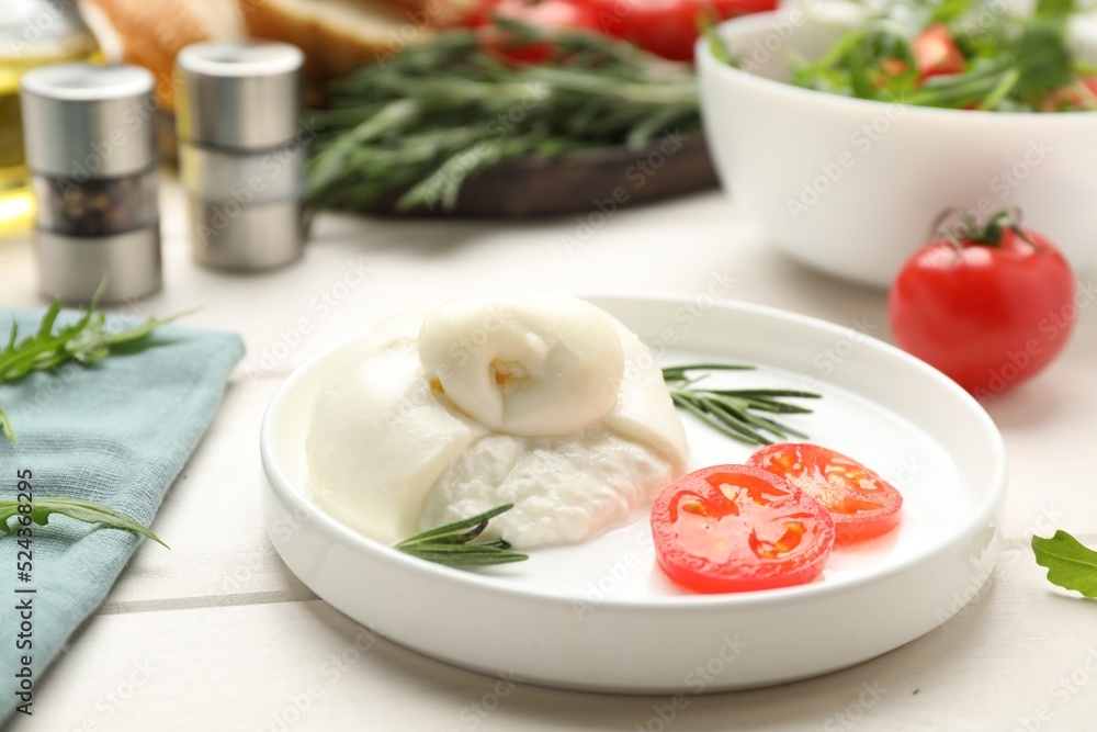 Delicious burrata cheese with rosemary and tomato on white wooden table Delicious burrata cheese with rosemary and tomato on white wooden table
