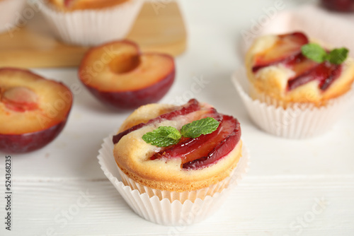 Delicious cupcakes with plums on white wooden table, closeup