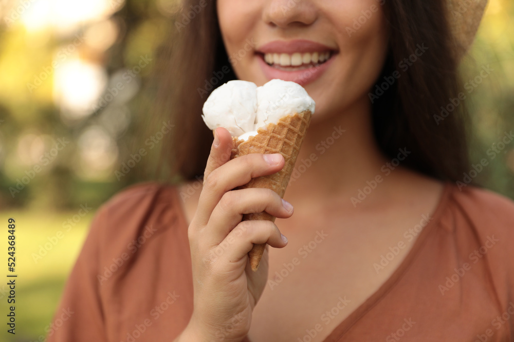 Young woman with delicious ice cream in waffle cone outdoors, closeup