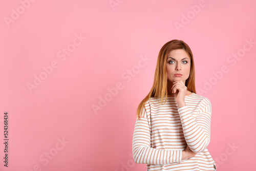 Pensive woman on pink background, space for text. Thinking about answer to question