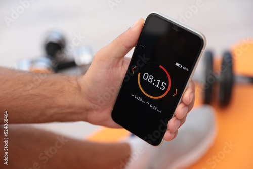 Man using fitness app on smartphone indoors, closeup