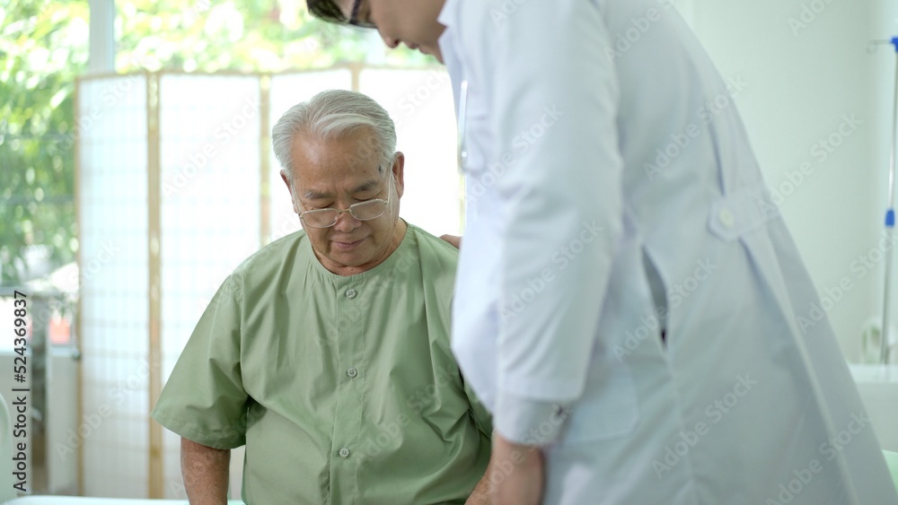 Elder Asian man sitting on the bed and talking to doctor about his physical injuries at his knees. Elder Asian man sitting on the bed and talking to doctor about his physical injuries at his knees.