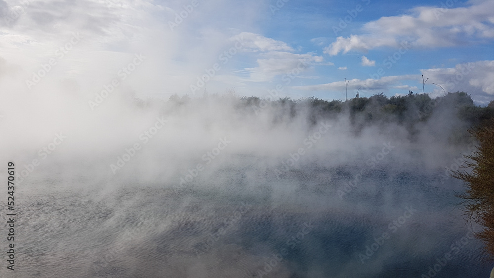 Steam over a thermal lake in Rotorua park, New Zealand