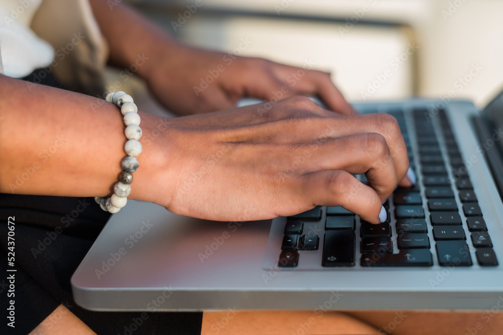 Closeup portrait of woman's hands working on her computer keyboard in outdoors