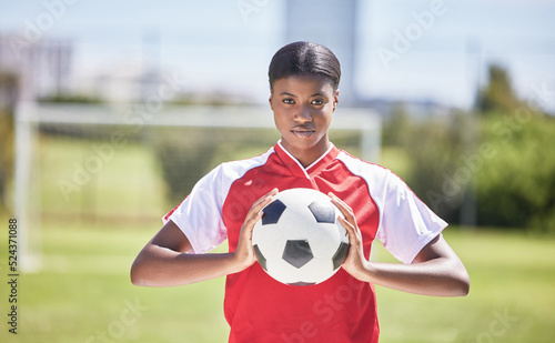 Soccer, football and sports with player, woman and athlete ready for a match, game or competition with ball on a pitch, field or stadium outdoor. Portrait of serious black female ready for training © Alexis Scholtz/peopleimages.com