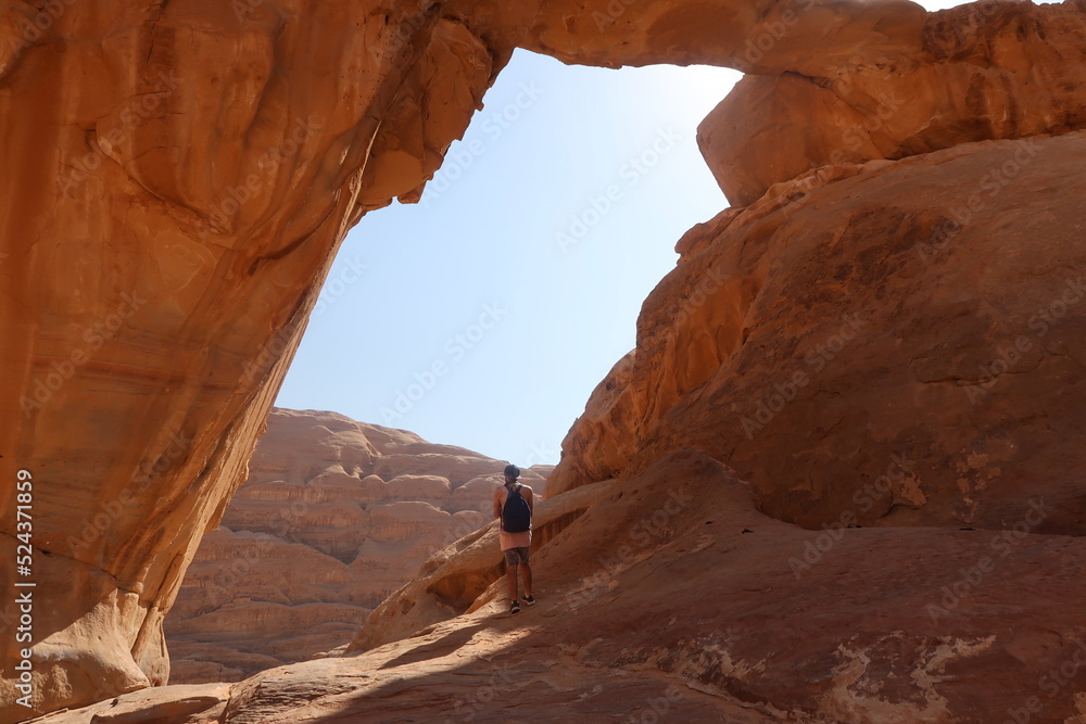 Hombre de viaje viendo al horizonte enmarcado por una roca