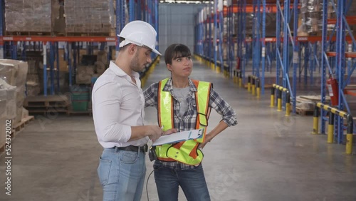 Young woman talking with manager while looking document report on clipboard and complain with angry in the warehouse at factory, employee discussion with boss about mistake, logistic concept.