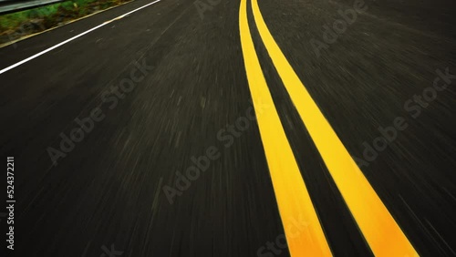Front pov view of fast car driving on asphalt road with double yellow lines converge
 photo