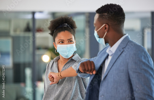 Covid, colleagues and greeting by touching elbows and wearing face masks and social distancing in an office. Friendly and diverse entrepreneurs preventing coronavirus infection spread at a workplace