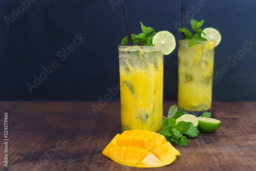Mango mojito in highball glass with sliced mango isolated on wooden table