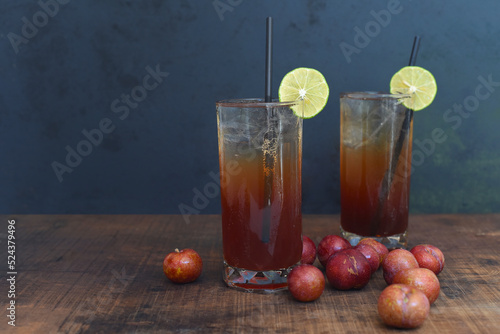 Plum wine highball cocktails with plums on wooden table and black background