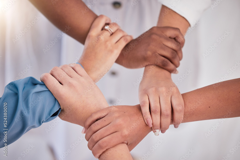 Diverse colleagues hands holding wrists from above in support of unity, loyalty and teamwork in the workplace. Professional business synergy, trust and collaboration working towards strategy goal. Diverse colleagues hands holding wrists from above in support of unity, loyalty and teamwork in the workplace. Professional business synergy, trust and collaboration working towards strategy goal.