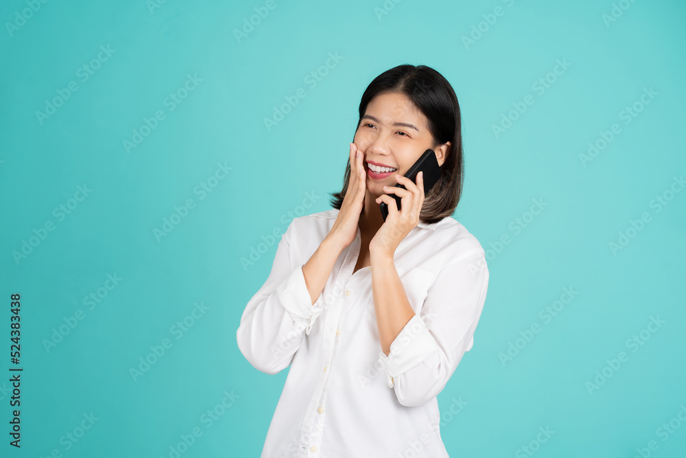 Surprised young Asia lady using mobile phone with smile broadly, dressed in casual clothing and looking at camera on bright green background. Surprised young Asia lady using mobile phone with smile broadly, dressed in casual clothing and looking at camera on bright green background.
