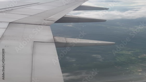 Aircraft window view wing flying from above air. Aerial view landscape airplane clouds.