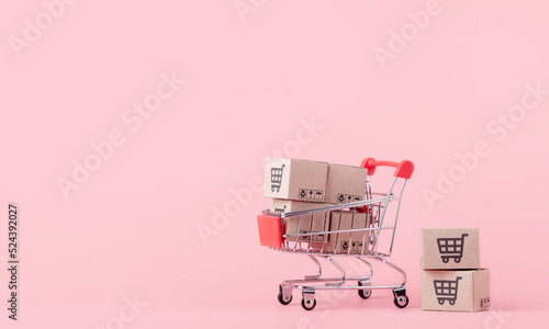 Fotografia, Obraz Shopping concept : Cartons or Paper boxes in red shopping cart on pink background