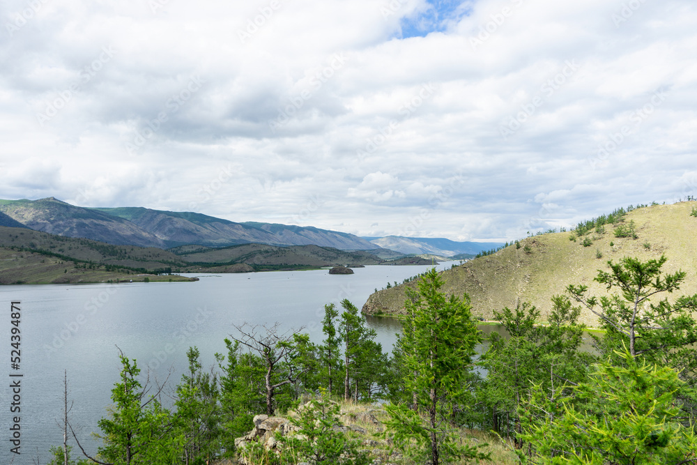 Lake, mountains, clouds, summer. A picturesque panoramic landscape over the lake, shot day after day with clouds in the sky.  Landscape of a summer day on the lake. 