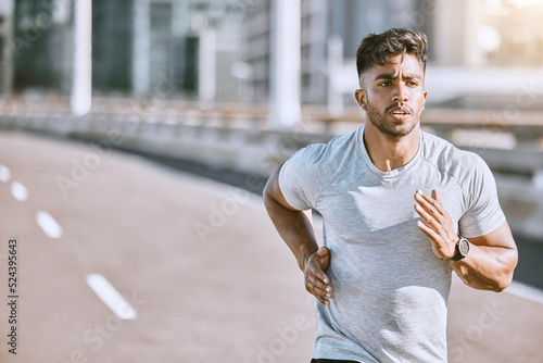 Runner running for fitness training on the street in urban city, doing cardio exercise and sport on the street. Serious, fit and sporty man jogging for health, exercising and doing routine run