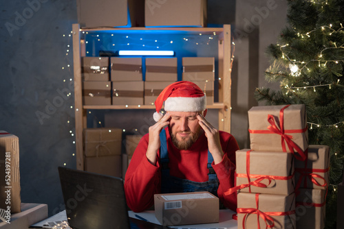Start up small business entrepreneur SME man in Santa hat working with box at home, frustated stressed small business owner, online marketing packaging Christmas box and delivery, SME stress photo