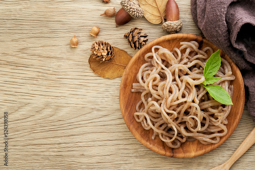 top view or flat lay concept of salad brown konjac noodle and green leaves in wooden plate on white table overhead background