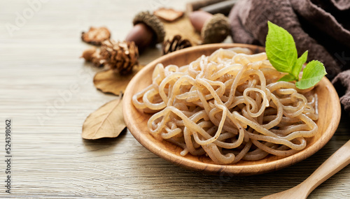 concept of salad brown konjac noodle and green leaves in wooden plate on white table background                                                                                       photo